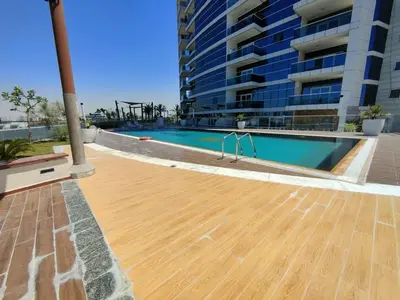 a swimming pool with a wooden floor in front of a building at WelHome - Relaxing and Fancy Studio Apt with City View in Dubai