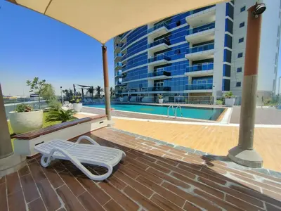 a lounge chair on a patio with a swimming pool at WelHome - Relaxing and Fancy Studio Apt with City View in Dubai