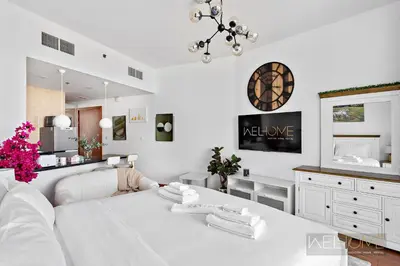 a white living room with a white table and a mirror at WelHome - Relaxing and Fancy Studio Apt with City View in Dubai