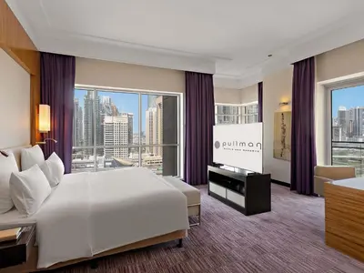 a bedroom with a large white bed and a large window at Pullman Dubai Jumeirah Lakes Towers in Dubai