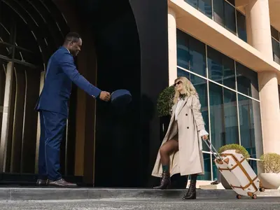 a man handing a hat to a woman in front of a building at Pullman Dubai Jumeirah Lakes Towers in Dubai