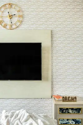 a television on a wall with a clock on it at The Smart Concierge - Seven Palm in Dubai