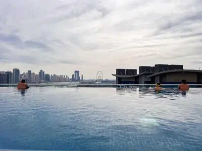 three people in a infinity pool with a city in the background at The Smart Concierge - Seven Palm in Dubai
