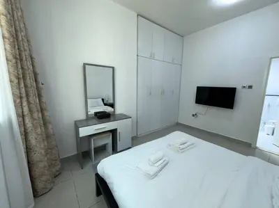 a white room with a bed and a mirror at Cozy 2 Bedroom Retreat in Dubai