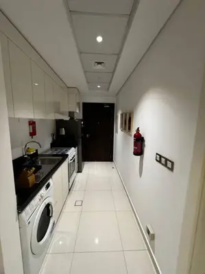 a small kitchen with a washing machine and a washer at Ghalia Studio Apartment in Dubai