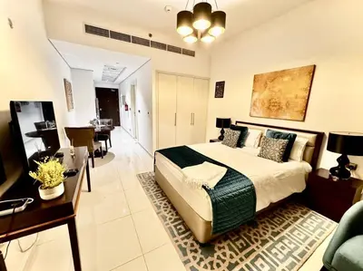 a bedroom with a large bed and a living room at Ghalia Studio Apartment in Dubai