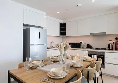 a kitchen with a wooden table and white cabinets at Luxury 2 BR Apartment, 5 Mins to Dubai Mall with Amazing view in DownTown Views 2 in Dubai