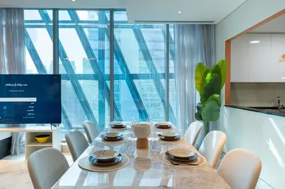 a dining room with a table and chairs and a large window at Escape24 2BR Huge Terrace with Canal View in Dubai