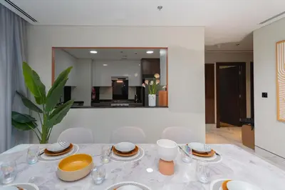 a dining room with a table and chairs and a mirror at Escape24 2BR Huge Terrace with Canal View in Dubai