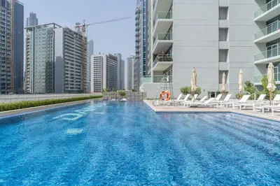 a swimming pool with chairs and a building at GuestReady - Modern living at Reva Residence in Dubai