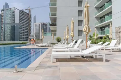 a row of lounge chairs and umbrellas next to a pool at GuestReady - Modern living at Reva Residence in Dubai