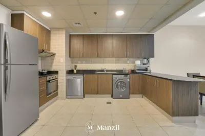 a large kitchen with wooden cabinets and a dishwasher at Manzil - 1BR in Elite Residence with Marina View in Dubai