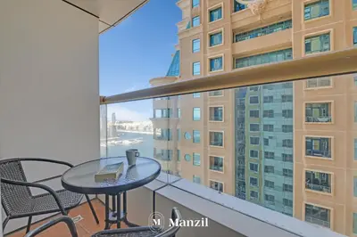 a balcony with a table and chairs and a large window at Manzil - 1BR in Elite Residence with Marina View in Dubai