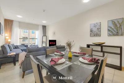 a dining room and living room with a table and chairs at Manzil - 1BR in Elite Residence with Marina View in Dubai