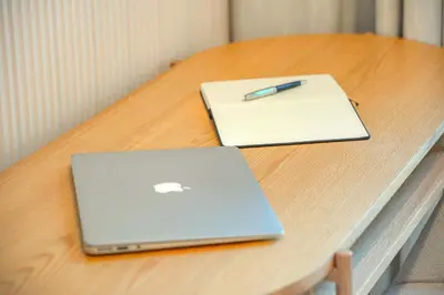 a laptop on a table with a pen and a notebook at Downtown Oasis Luxury One-bed in Downtown Dubai in Dubai