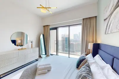 a bedroom with a blue couch and a large window at Burj Royale - Central Two Bedroom in Dubai