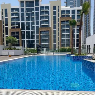 a large blue swimming pool in front of tall buildings at Beautiful 1 BR with Gym, Pool & Kid's Playground in Dubai
