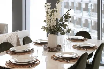 a dining room table with plates and a vase with flowers at Stunning 2BR Full Burj Khalifa Views 5min walk to Dubai Mall in Dubai
