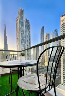 a table and chairs on a balcony with a view of a city at Stunning Burj and Fountain View - 2BR in Dubai