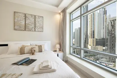 a bedroom with a large bed with a large window at Stunning Burj and Fountain View - 2BR in Dubai