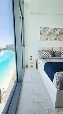 a bedroom with a bed and a view of the beach at Spectacular Lagoon Apartment in Dubai