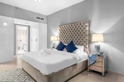 a white bedroom with a large bed with blue pillows at First Class 1BR Modern & Stylish Living in Dubai