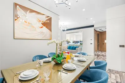 a dining room with a wooden table and blue chairs at Dubai 2BR Flat, Marina Views, Pool Access, Parking, Walk to Mall in Dubai