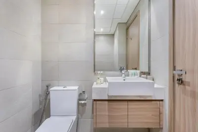 a bathroom with a sink and a toilet and a mirror at Lux Stu Bright Urban Escape Stay Near Downtown in Dubai