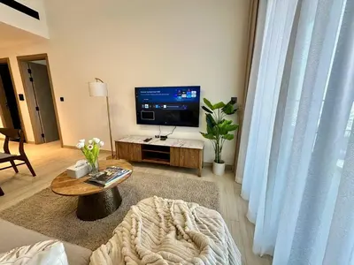a living room with a large tv and a couch at Cozy Elegant 1br Balcony, Pool Access, Parking in Dubai