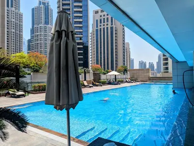 an umbrella next to a swimming pool with buildings at Downtown Studio near Dubai Mall in Dubai