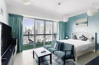 a bedroom with a bed and a couch and a large window at Downtown Studio near Dubai Mall in Dubai