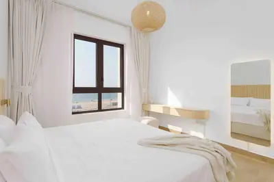 a white bedroom with a bed and a window at Beach stylish full sea view in Dubai