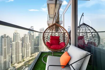 a balcony with two hanging chairs and a view of a city at Best Burj Khalifa View Balcony Apartment with 64th-Floor Infinity Pool in Paramount Hotel Midtown in Dubai