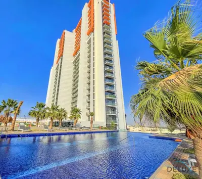 a hotel with a swimming pool and palm trees at Peaceful 1BR at Golf Vita A Damac Hills by Deluxe Holiday Homes in Dubai