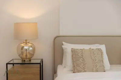 a bedroom with a bed with a lamp on a night stand at Stylish 2BR Apartment at Dubai Hills with Pool Access By ĀYA Boutique in Dubai