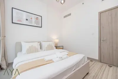 a white bedroom with a large bed with two towels on it at Stylish 2BR Apartment at Dubai Hills with Pool Access By ĀYA Boutique in Dubai