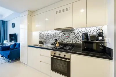 a kitchen with white cabinets and a microwave at A Living - Luxury Studio Apartment in Aykon City Canal Views, Business bay in Dubai