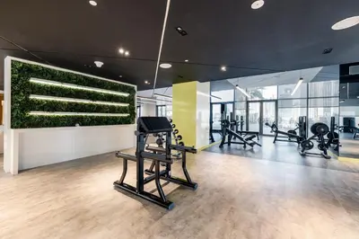 a gym with treadmills and a green wall at A Living - Luxury Studio Apartment in Aykon City Canal Views, Business bay in Dubai