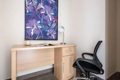 a desk with a chair and a painting on the wall at Frank Porter - Eleganz 5 in Dubai