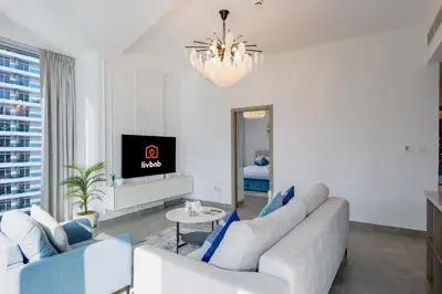 a living room with white furniture and a chandelier at Deluxe 1BR Corner Suite with Marina Views in Dubai