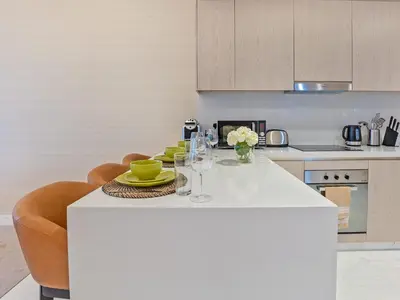a kitchen with a white island with a table and chairs at Palm Tower Luxury 1BR Sea View Suites with 5 Star Hotel Amenities in Dubai