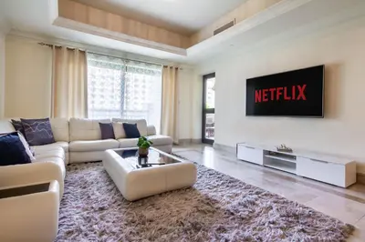 a living room with a couch and a tv on a wall at Bespoke Holiday Homes - Palm Jumeirah- 1 Bedroom North Residence in Dubai