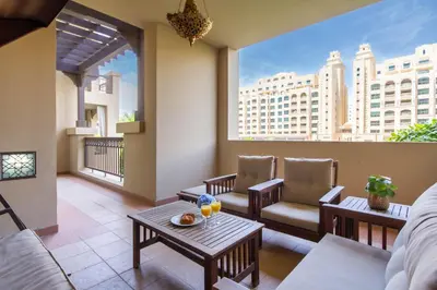 a living room with a balcony with chairs and tables at Bespoke Holiday Homes - Palm Jumeirah- 1 Bedroom North Residence in Dubai