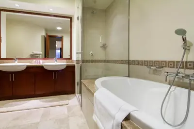 a bathroom with two sinks and a tub and a mirror at Bespoke Holiday Homes - Palm Jumeirah- 1 Bedroom North Residence in Dubai