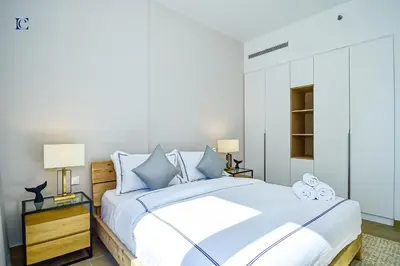 a white bedroom with a large bed and two lamps at Luxury Escapes - Sea View 1Bed Apartment in Port de Lamer in Dubai