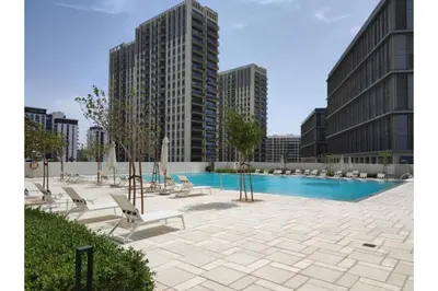 a pool with lounge chairs and a building at HAVN - 1 Bedroom in Collective, Dubai Hills Estate in Dubai
