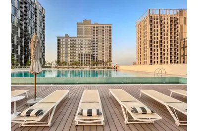 a pool with lounge chairs and an umbrella on a deck at HAVN - 1 Bedroom in Collective, Dubai Hills Estate in Dubai