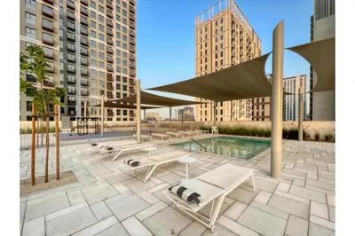 a pool with benches and a pavilion with buildings at HAVN - 1 Bedroom in Collective, Dubai Hills Estate in Dubai