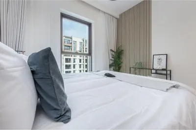 a white bed with pillows in a bedroom with a window at HAVN - 1 Bedroom in Bayshore 2, Creek Beach in Dubai