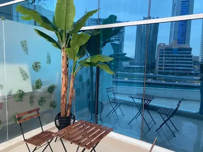 a balcony with a bench and a palm tree at JBR Walk Full Apartment Marina View in Dubai